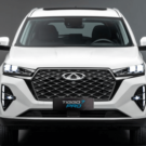 Frente do Novo Tiggo 7 Pro híbrido branco com os faróis acesos.