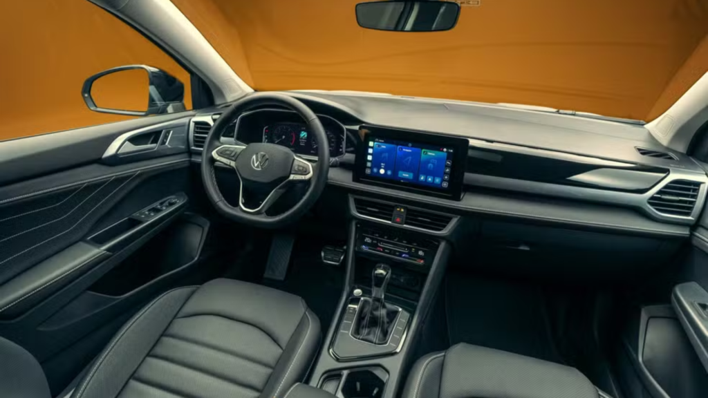 Interior do Volkswagen Taos 2026 com o painel multimidia ligado e no fundo laranja.
