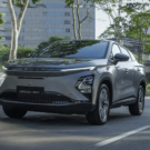 Novo Omoda 5 HEV cinza em movimento na estrada com os faróis acesos.