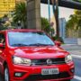 Frente do Volkswagen Gol vermelho com os faróis acesos.