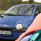 Renault Twingo elétrico no canto da tela e um Twingo azul na estrada no fundo.