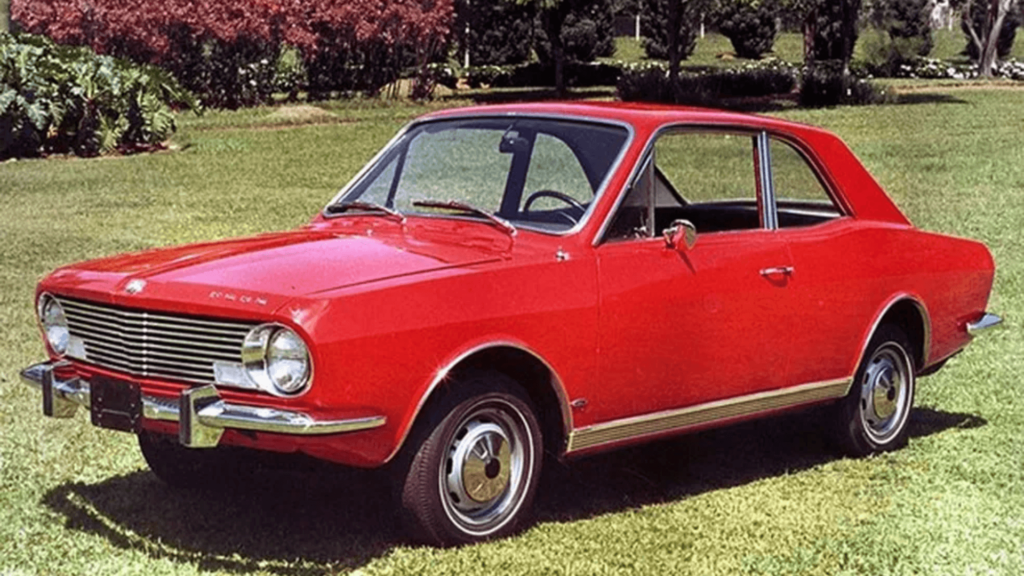 Ford Corcel vermelho parado na diagonal em cima de um gramado.
