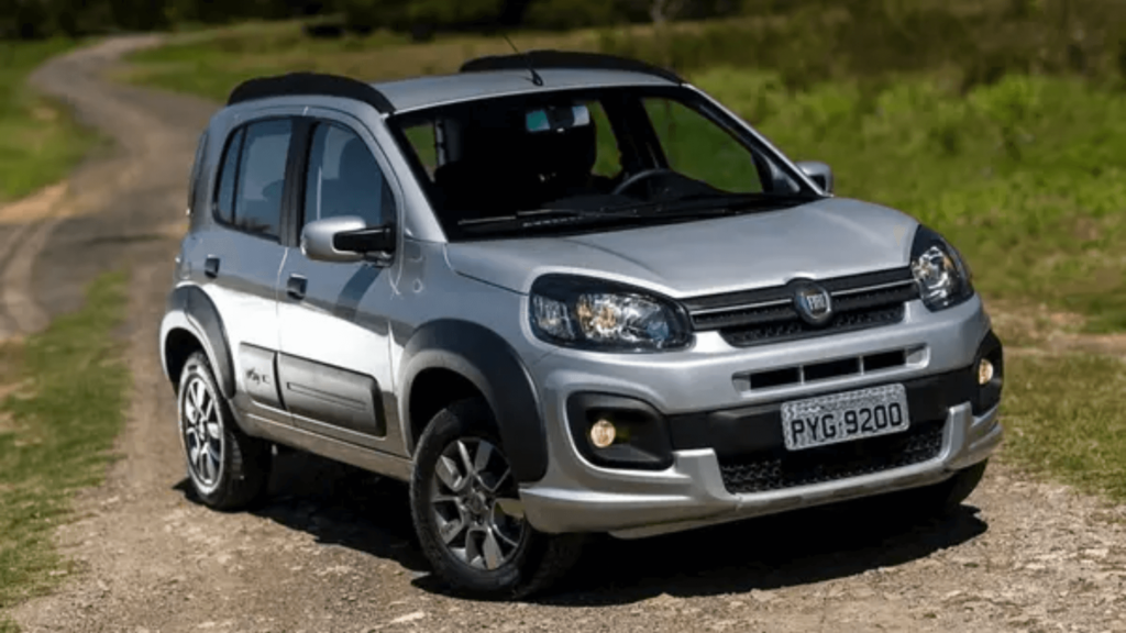 Fiat Novo Uno prata parado na diagonal em uma estrada de chão.
