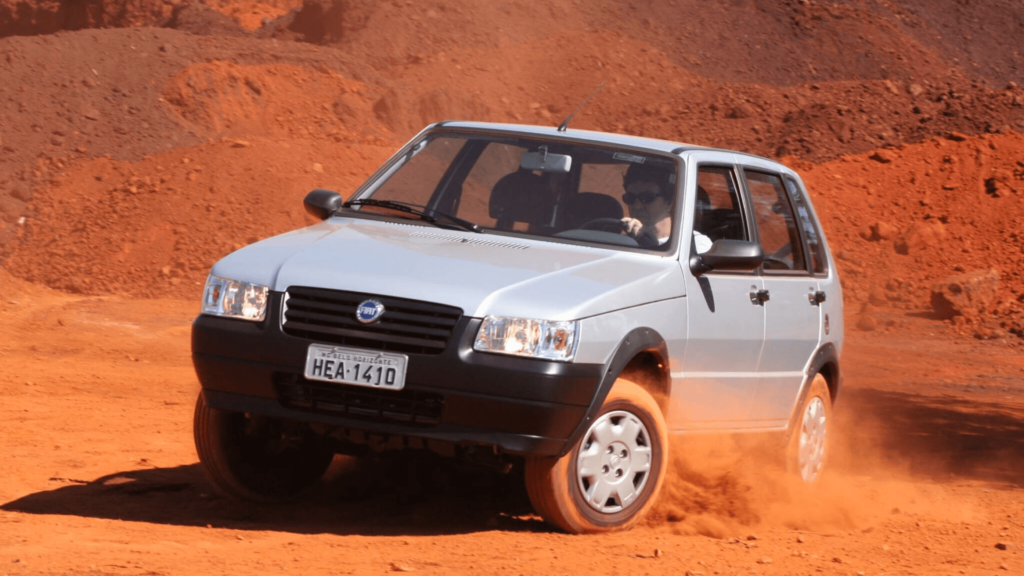 Fiat Uno Mille prata derrapando na areia.