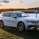 Tiguan Allspace R-Line branco parado na diagonal com um lago no fundo.
