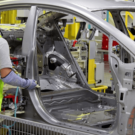 Dois homens trabalhando na montagem de um carro prata.