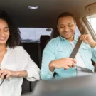 Duas pessoas no carro com cinto de segurança.