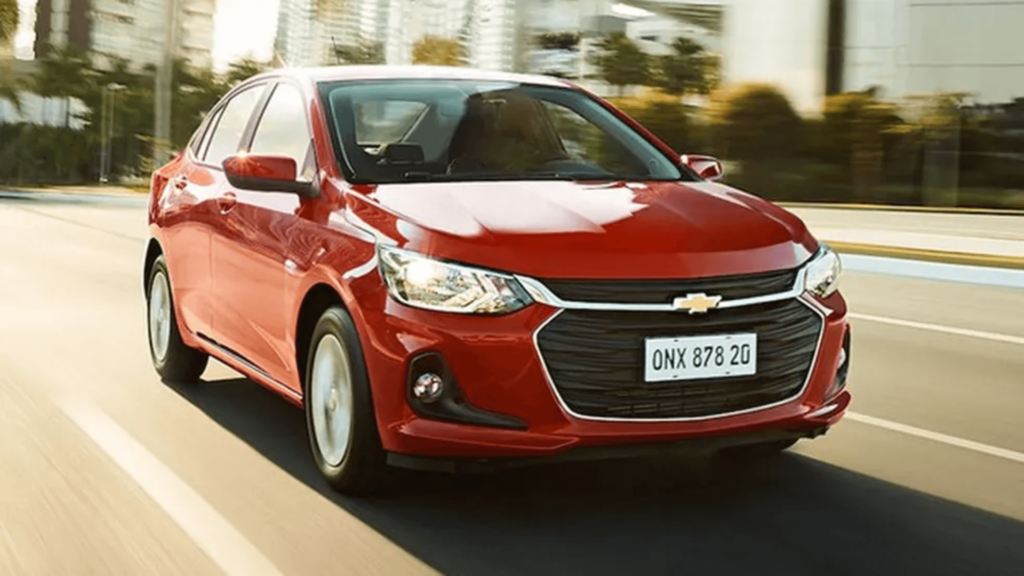 Onix Plus vermelho em movimento na estrada.