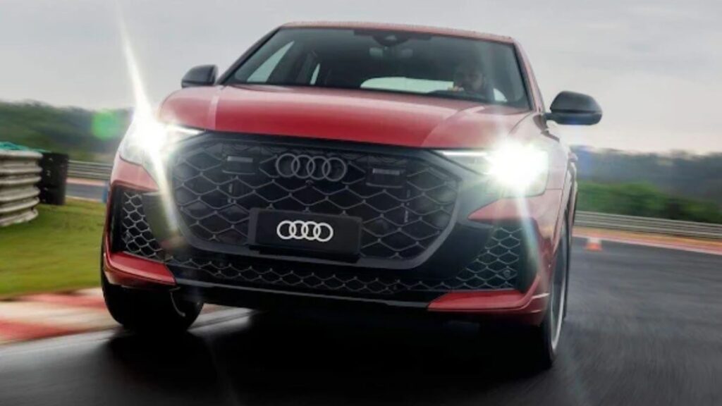 Audi RS Q8 Performance 2026 vermelho em movimento com os faróis acesos.