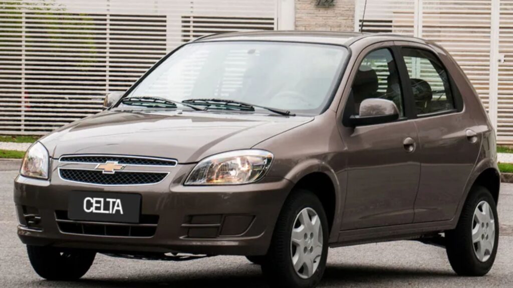 Chevrolet Celta marrom parado na diagonal.