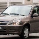 Chevrolet Celta marrom parado na diagonal.