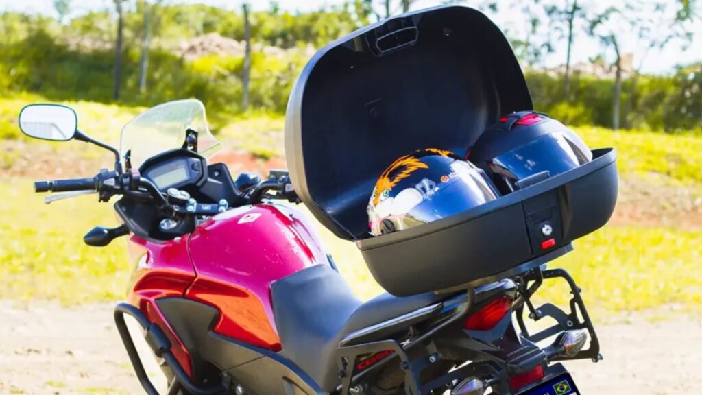 Moto vermelha com baú com dois capacetes.