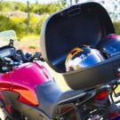 Moto vermelha com baú com dois capacetes.