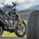 Pneu de uma moto com uma moto no fundo parada.