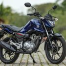 Honda CG 160 azul parado na diagonal.