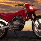 Honda CRF 300F vermelho parado na diagonal.