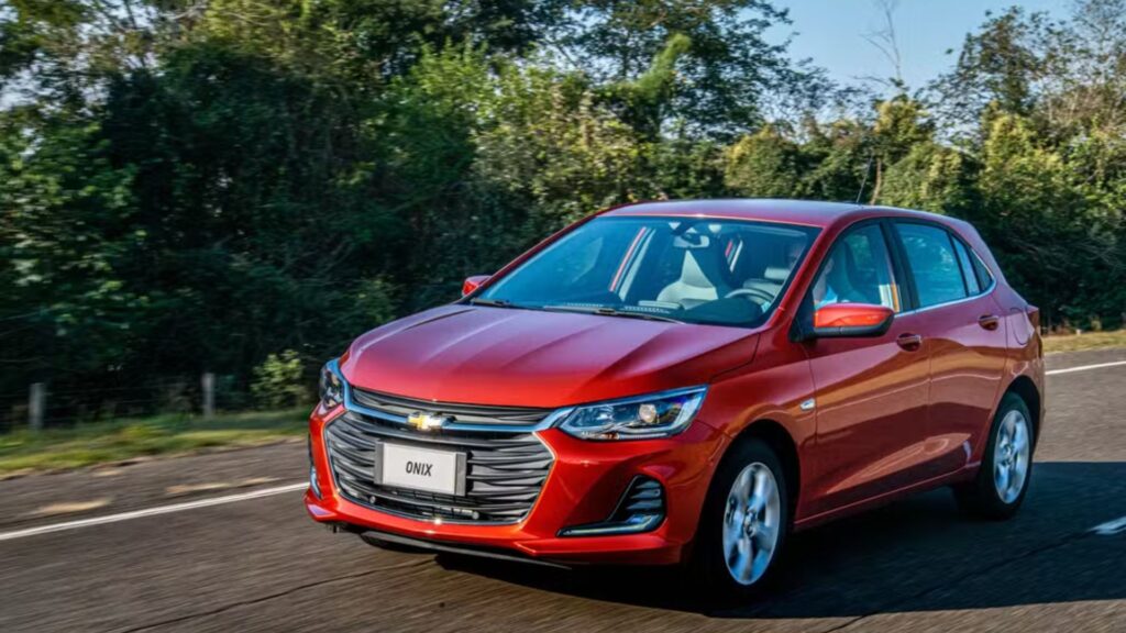 Chevrolet Onix vermelho em movimento na estrada.