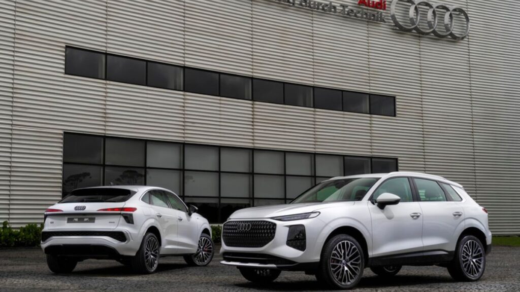 Dois Audi Q3 brancos em frente a fábrica.