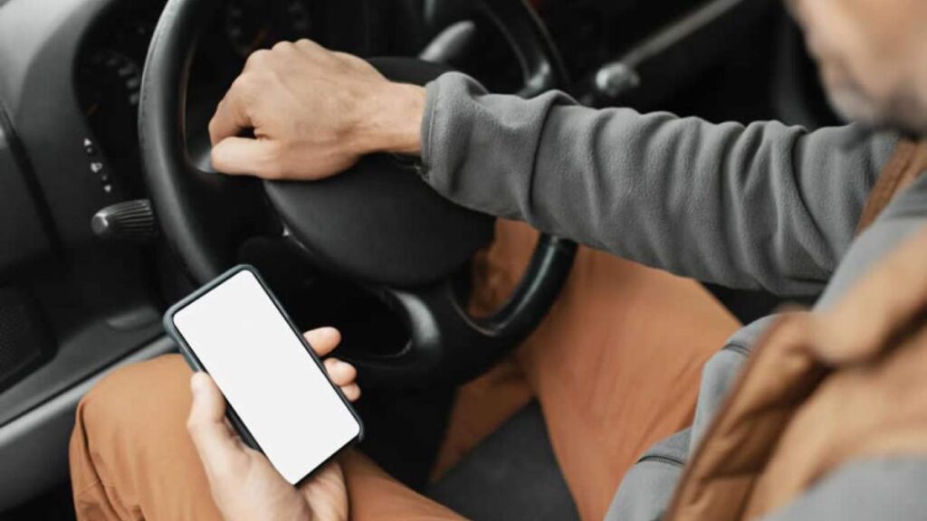 Homem usando celular no carro.