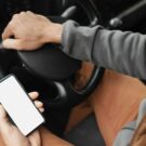 Homem usando celular no carro.